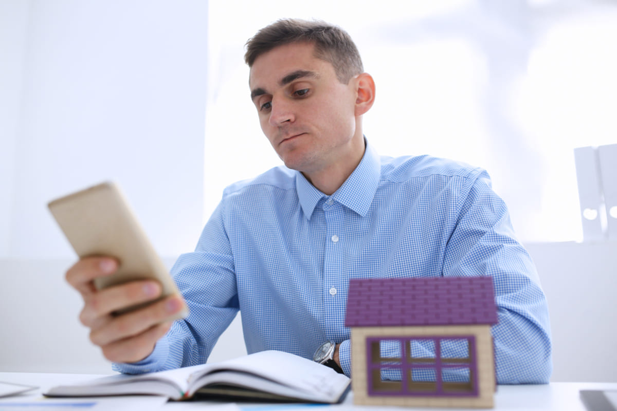 A businessman realtor holds a smartphone in hand to communicate with tenants