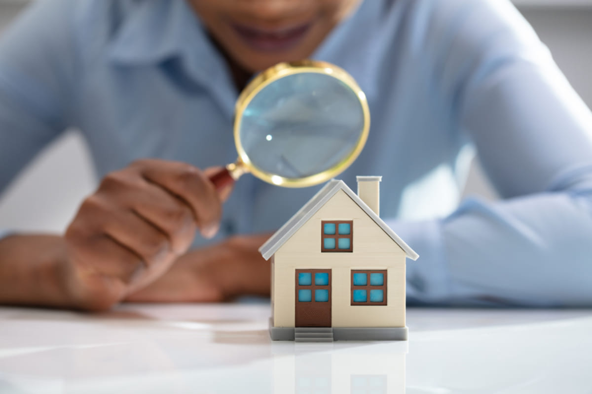 A woman with a magnifying glass looking at a house, property inspections concept