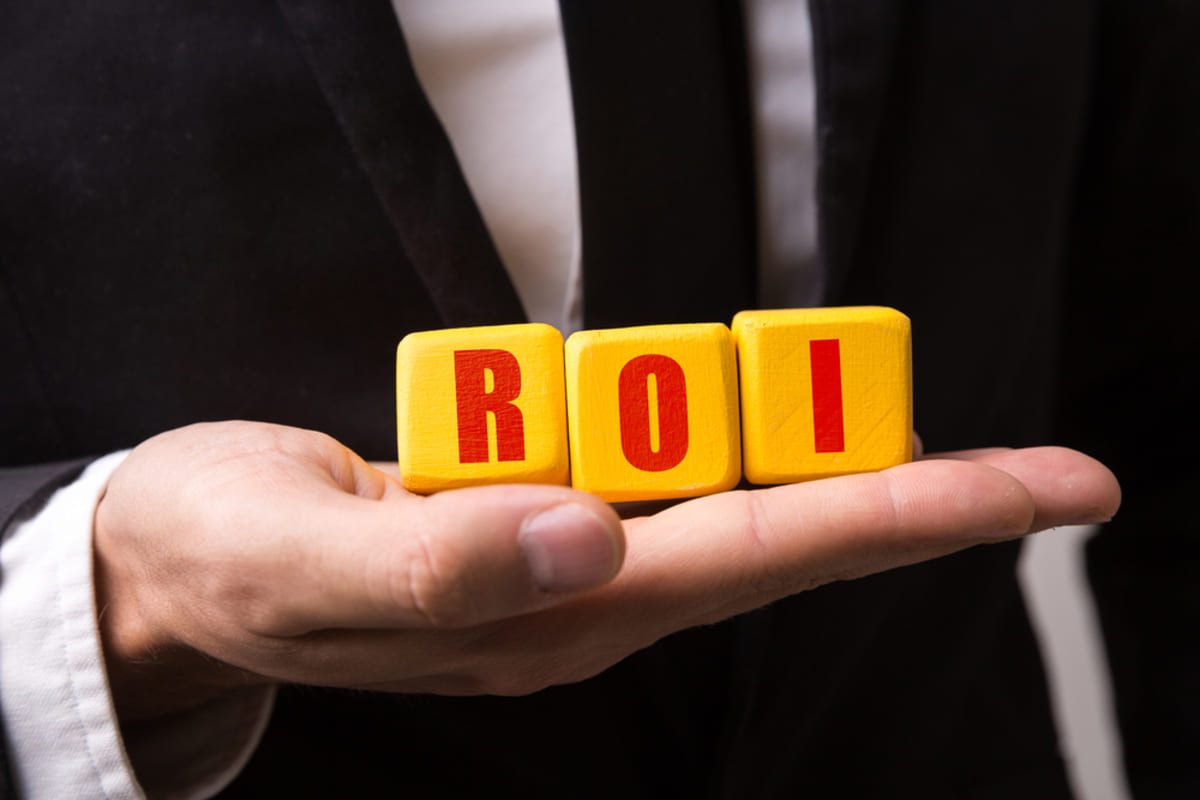 Businessman hand holding wooden blocks spelling ROI