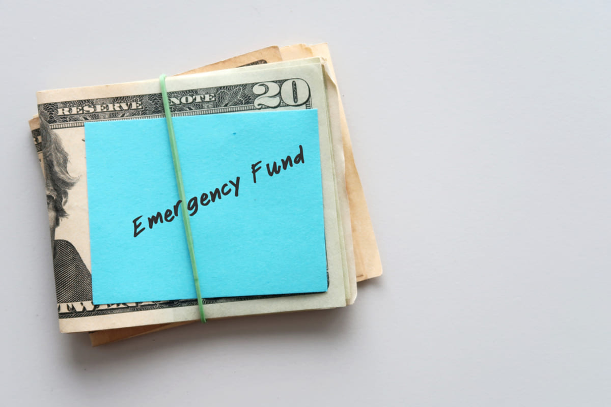 Cash with blue note saying Emergency funds. Saving for emergency concept