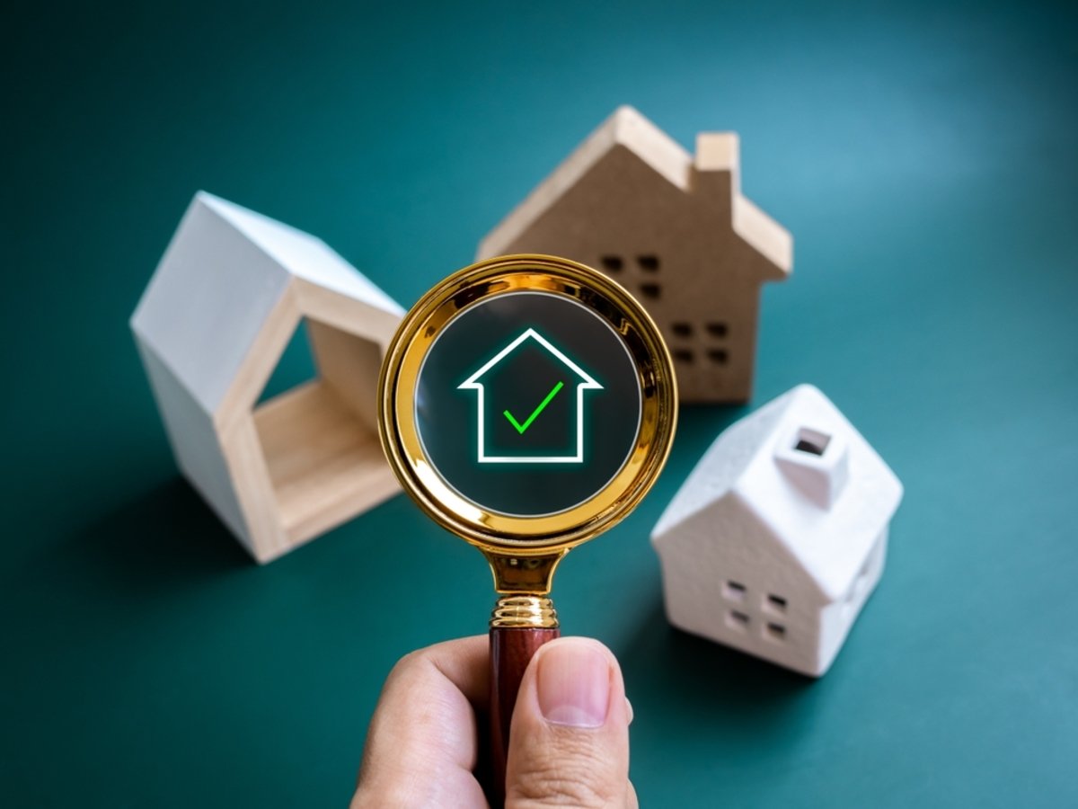 Digital home symbol with green check mark on gold magnifying glass in hand with many kinds of house