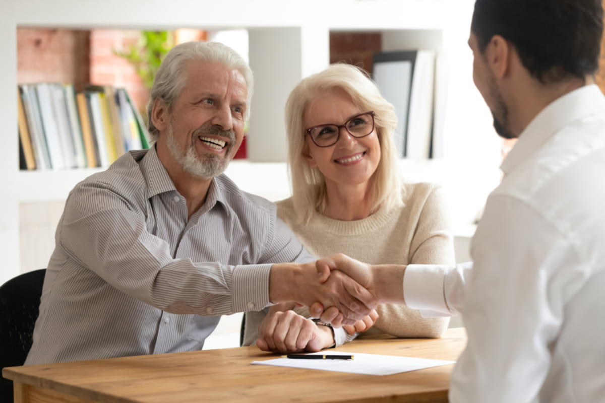 Happy senior old couple handshake property manager