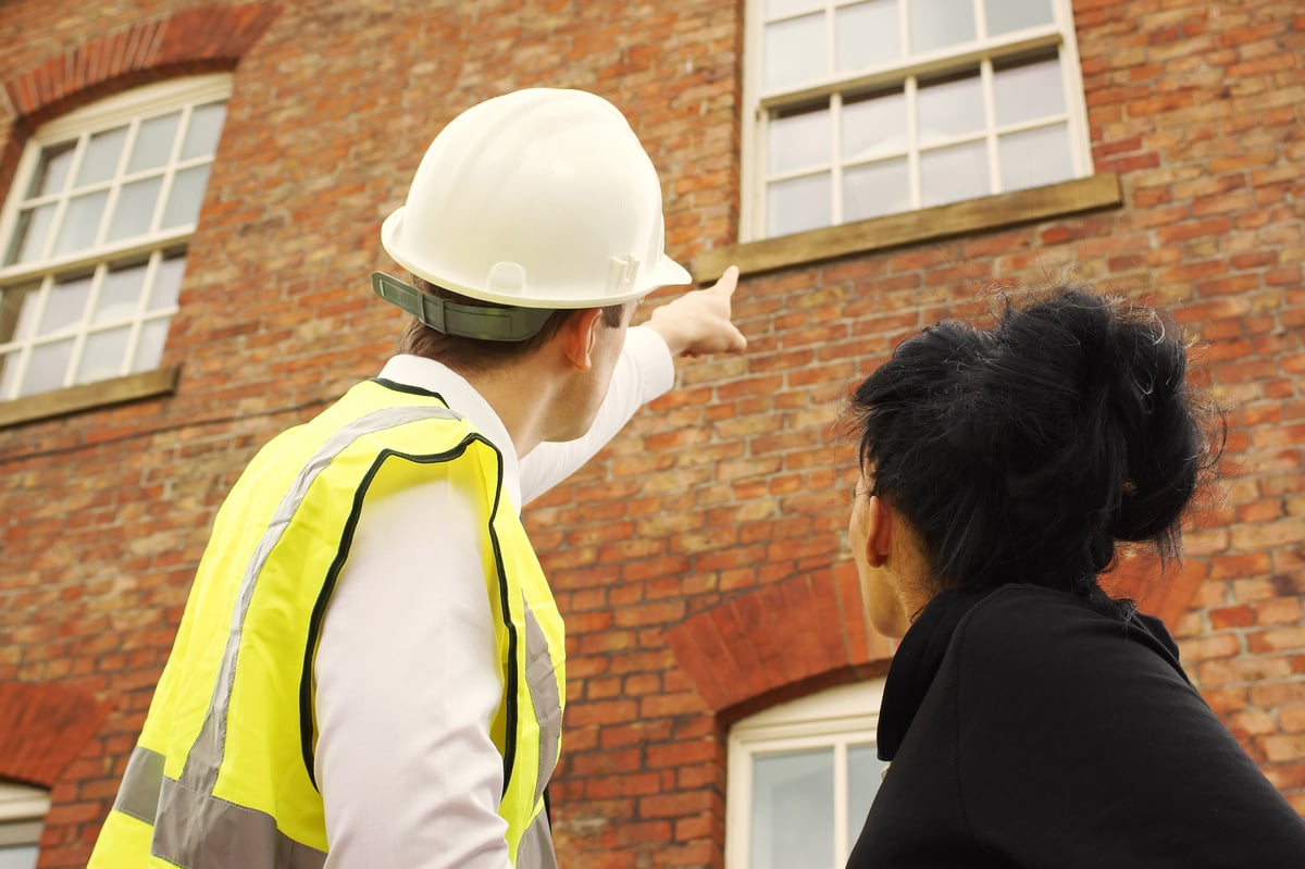 A rental property maintenance professional points to a building. 