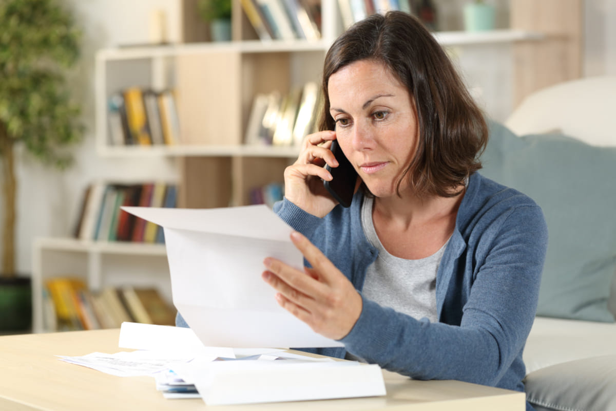 Serious adult woman checking letter calling on smartphone sitting at home