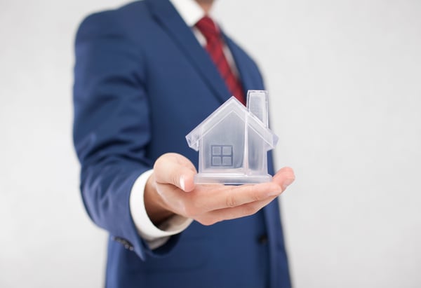 Businessman with crystal house in hand