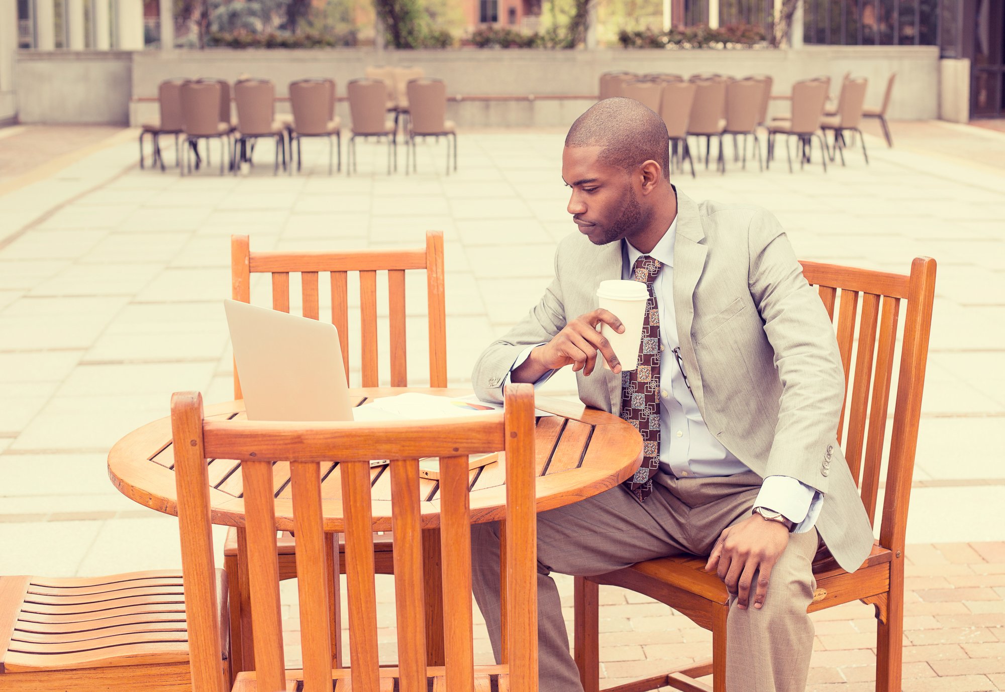 Businessman working outdoors reading documents drinking coffee