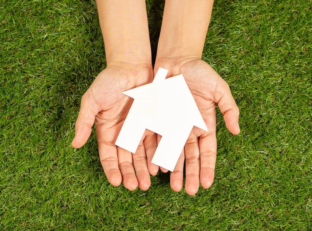 Hands holding a model house, Charleston property management company concept.