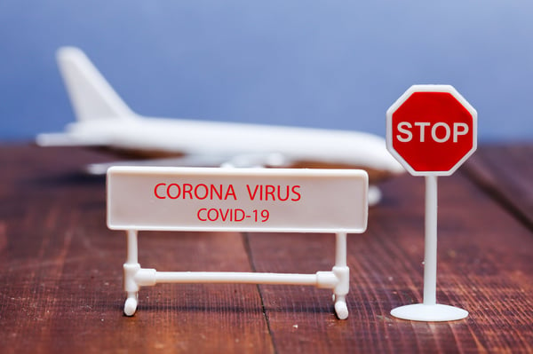 Corona virus sign on foreground with toy aeroplane in back