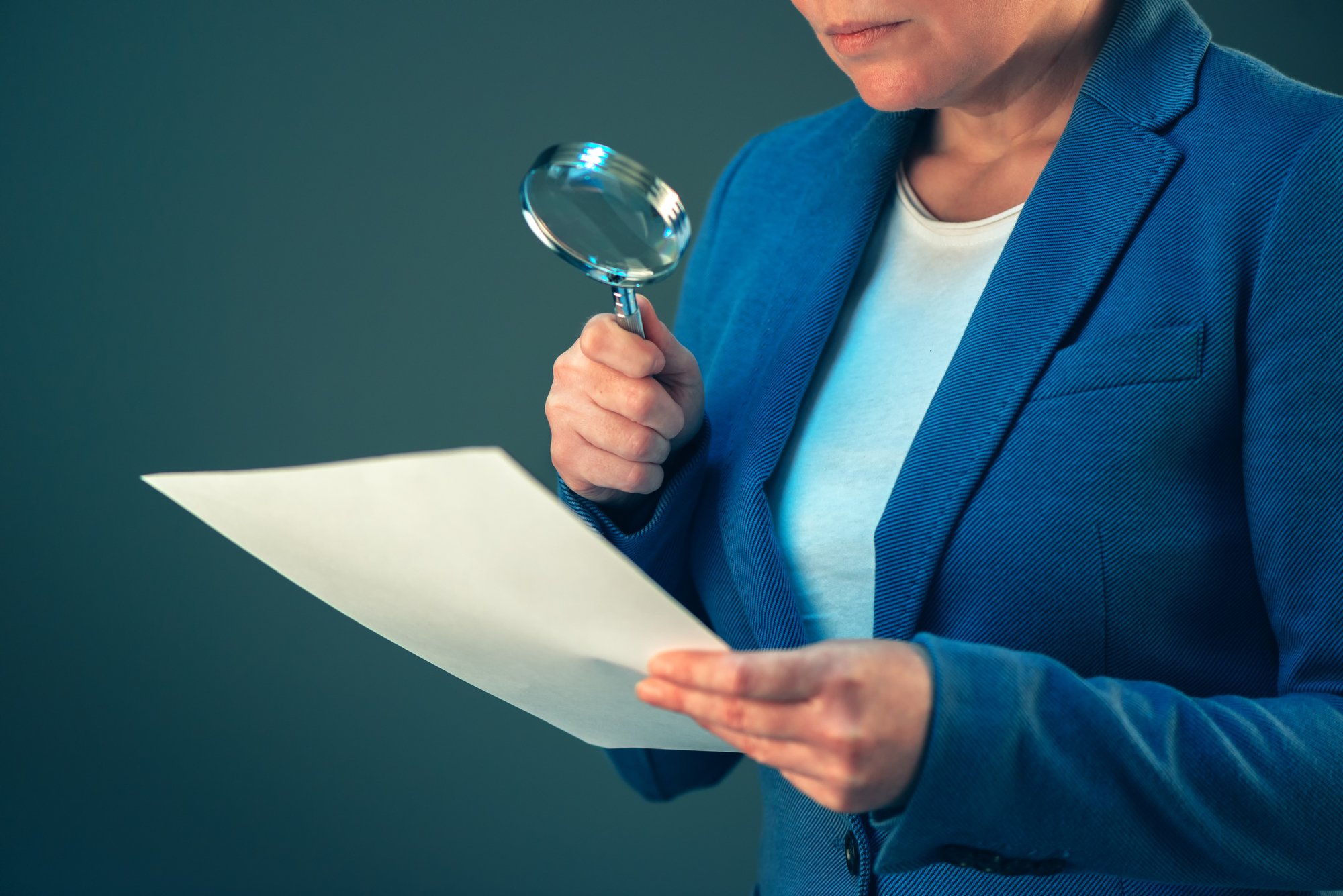 Female tax inspector looking at document with magnifying glass