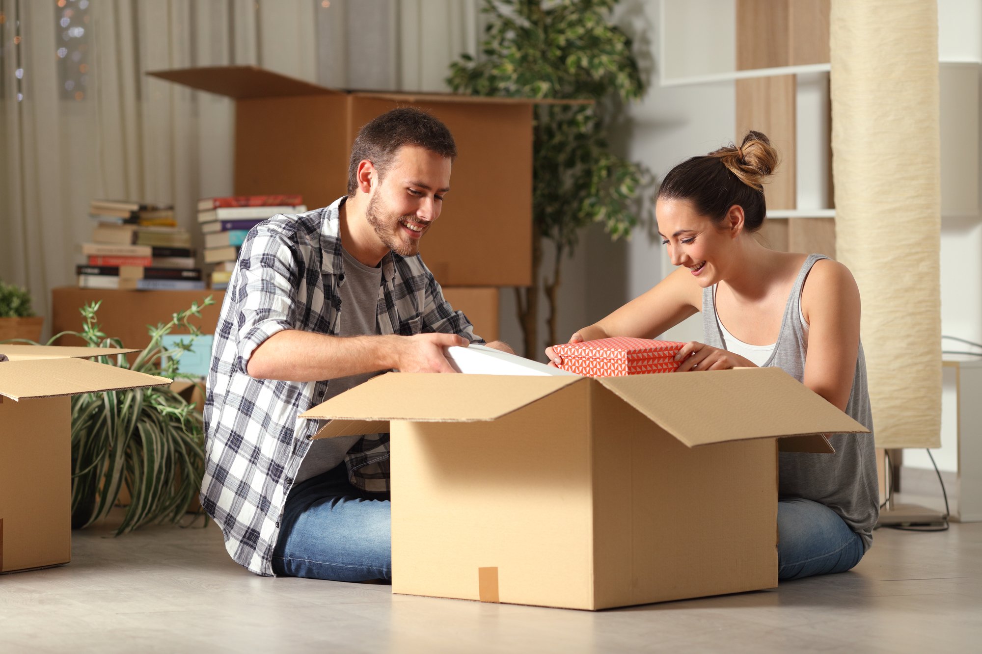 Happy couple unboxing belongings moving house on the floor