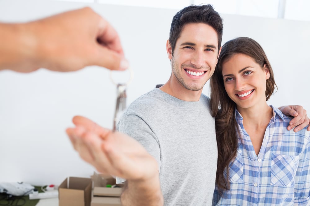 Happy couple receiving a house key, how to screen tenants concept. 