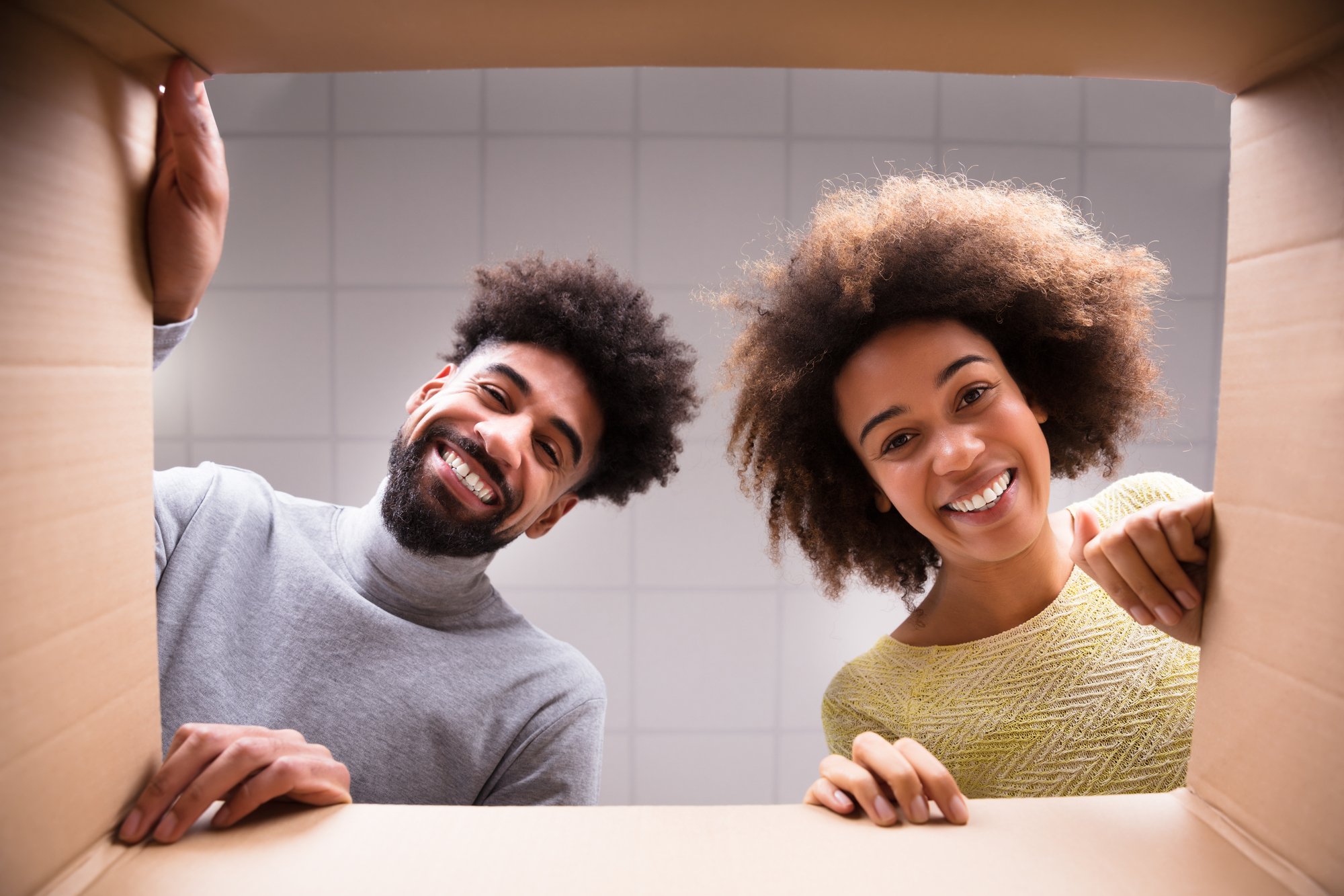 Low Section View Of A Young Happy Couple Looking Inside Cardboard Box