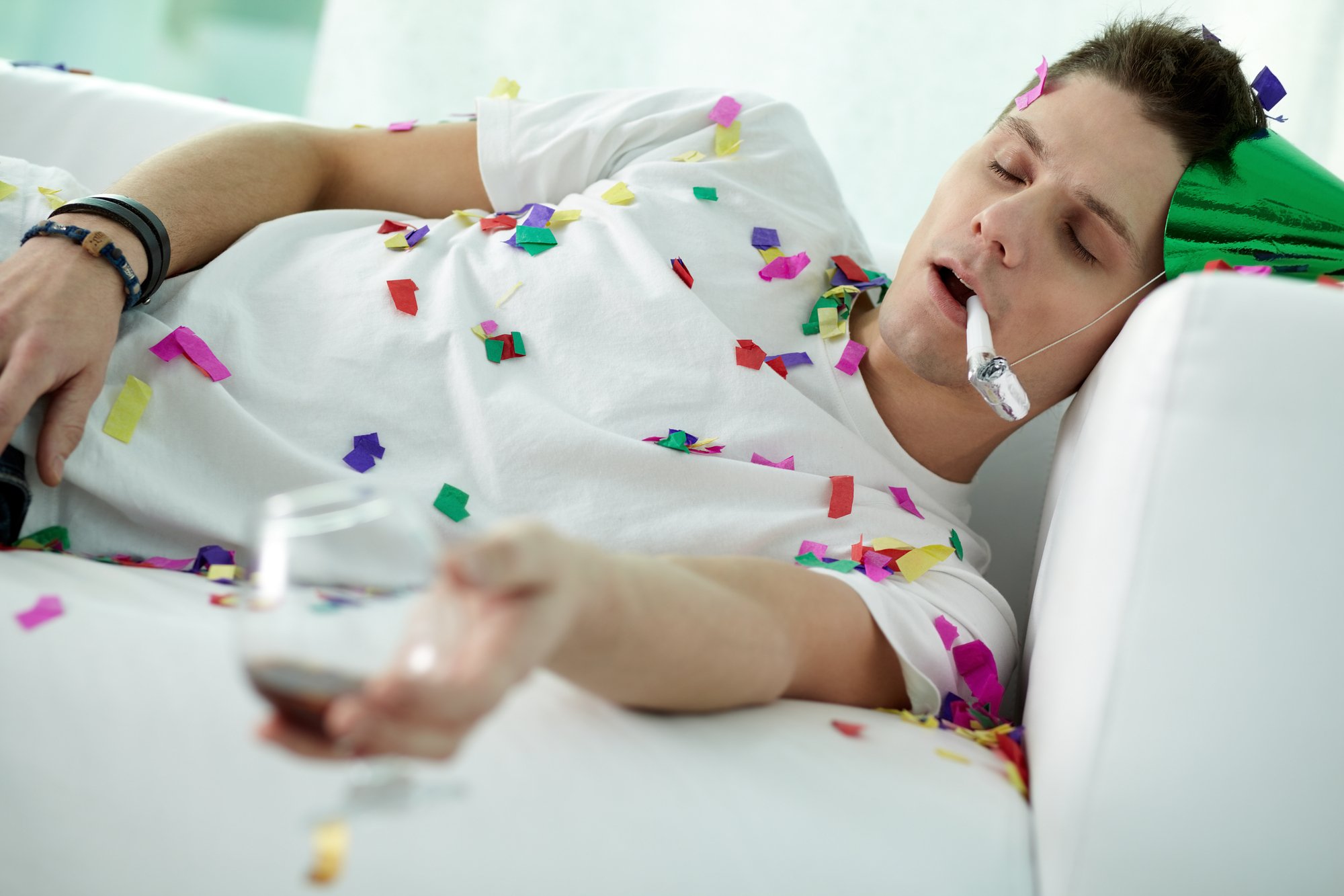 Man sleeping on sofa in party hat