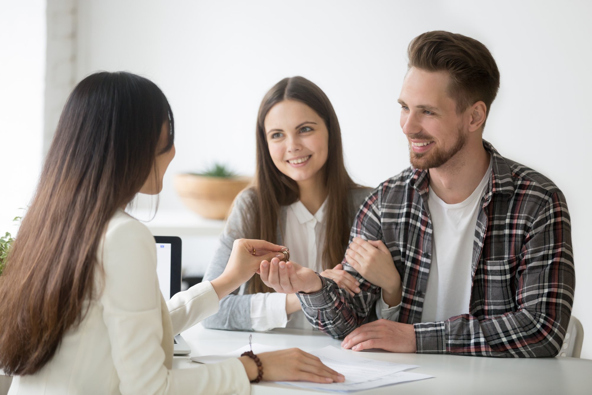 Smiling couple receiving keys to first apartment together