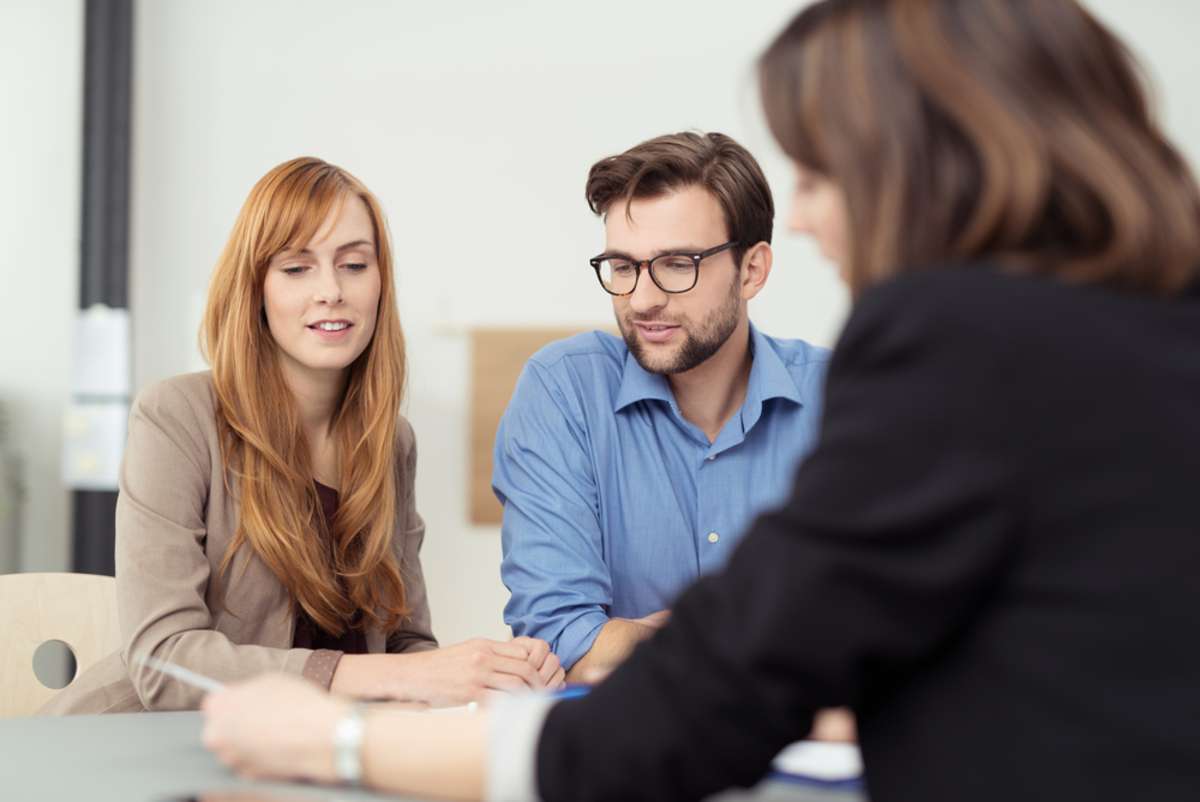 Property manager reviewing documents with couple, rental management companies concept