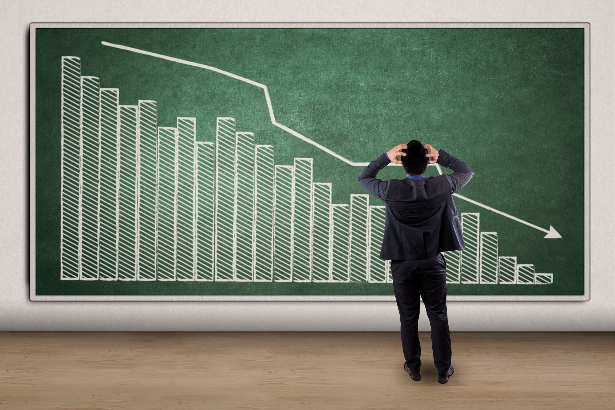 Stressful businessman looking at a declining graph