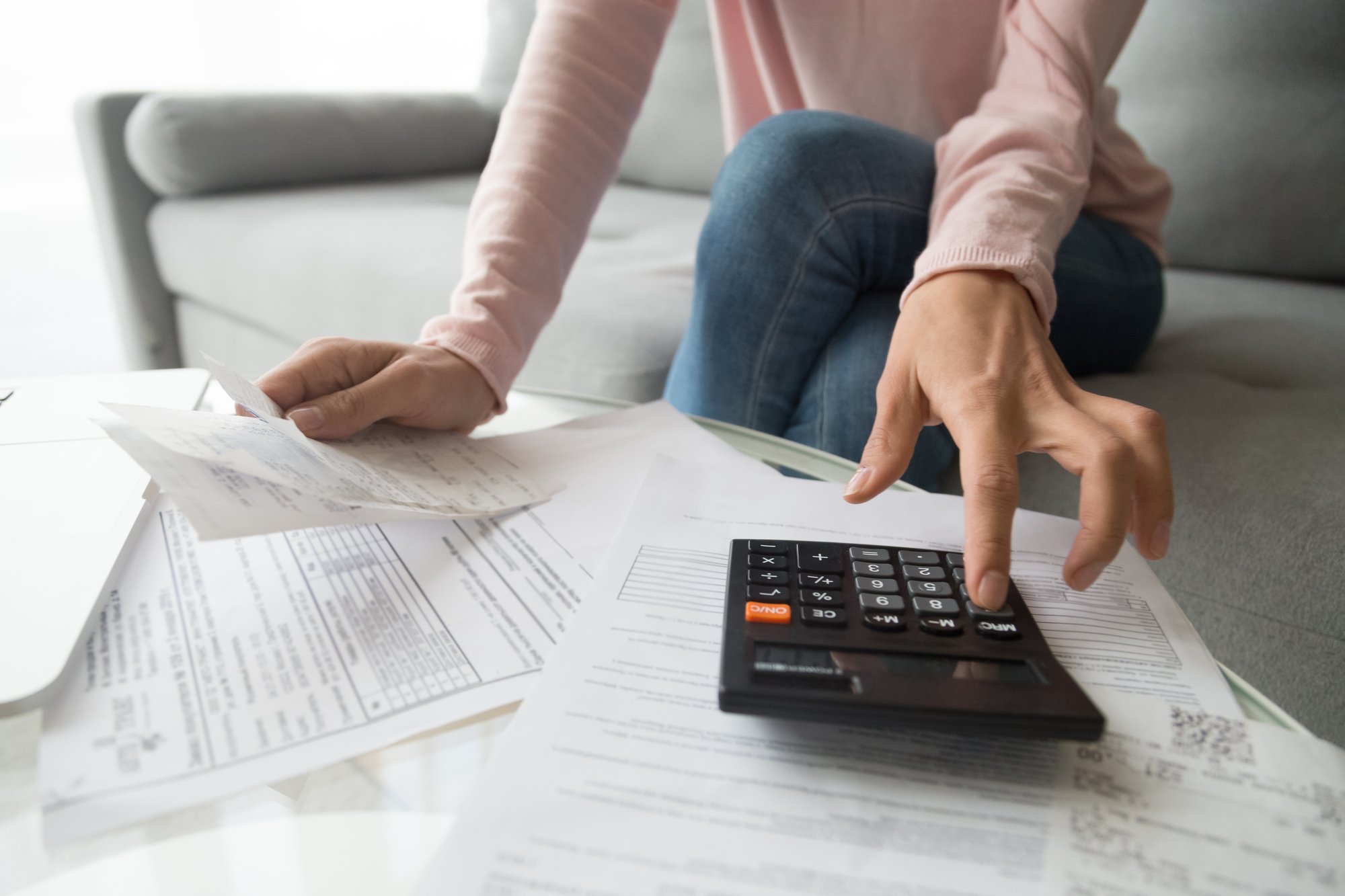 Woman holding bills using calculator manage finances, close up view