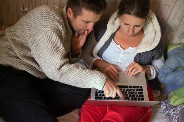Young couple in bed with laptop being sad, Quarantine or stay home