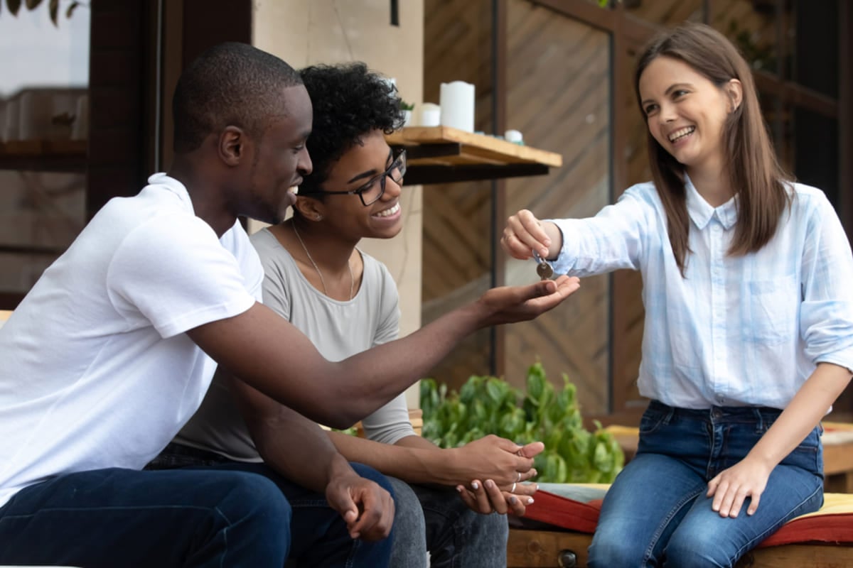 A woman handing keys to two tenants