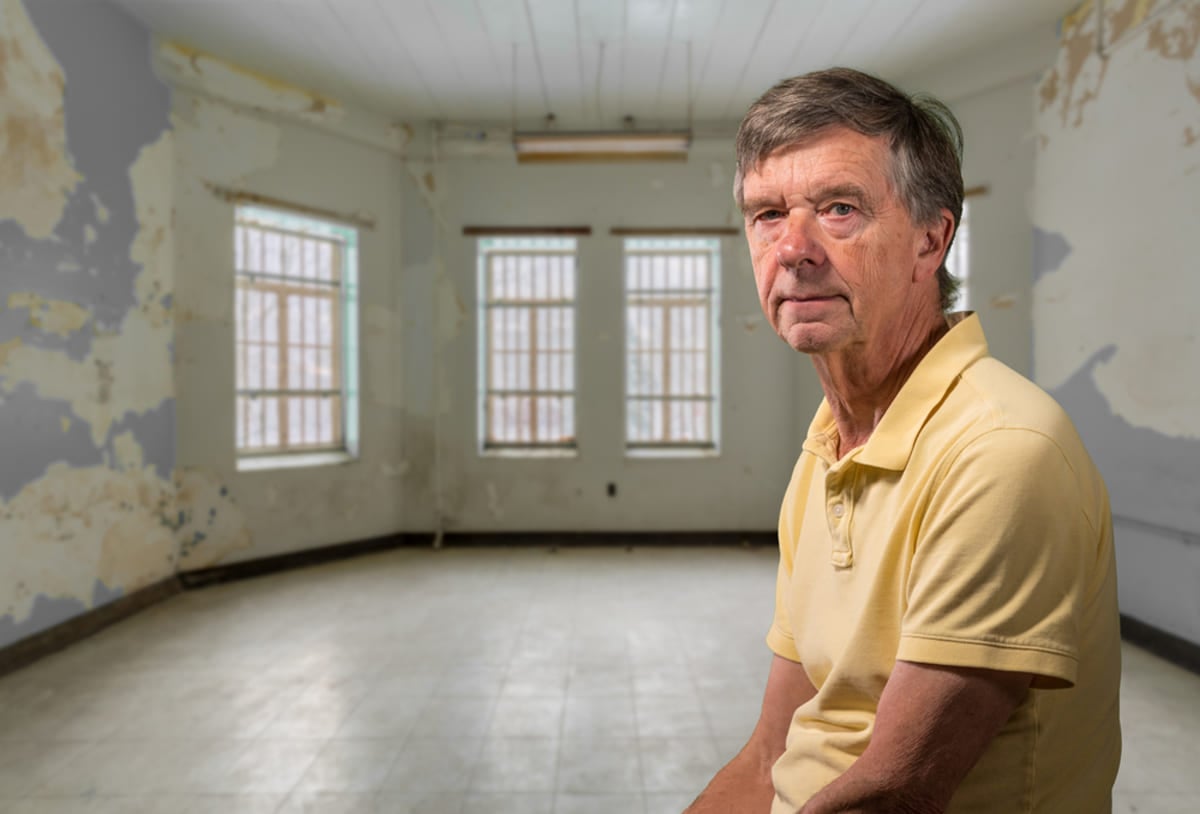  Landlord sitting in empty room of his damaged rental property.
