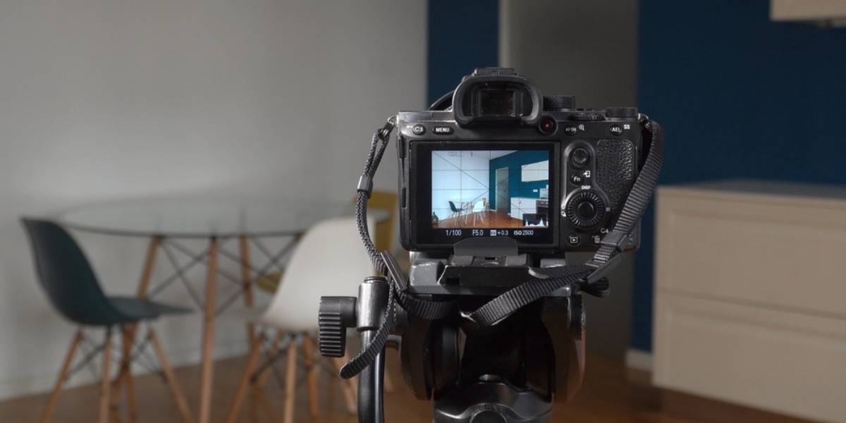 Man photographer taking pictures indoor in living room - real estate home photography and professional video to sell the house apartment