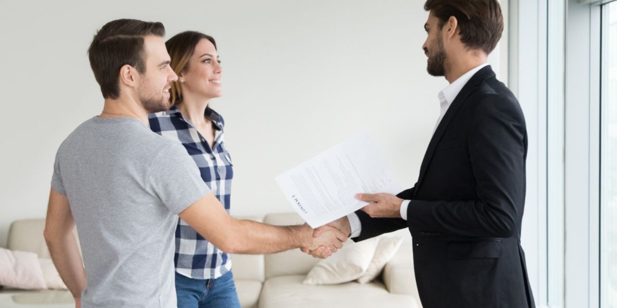 Realtor or landlord handshaking couple buyers tenants make real estate deal holding rental agreement