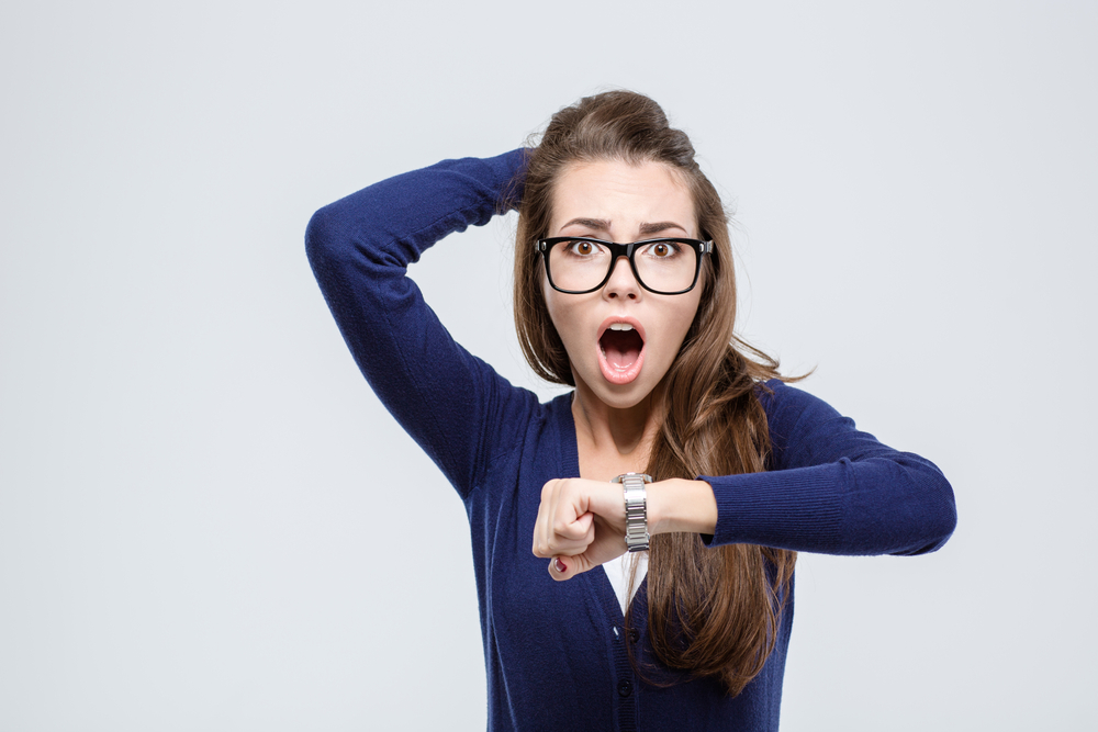 A shocked young woman with a watch, time for a Charleston property management company concept. 
