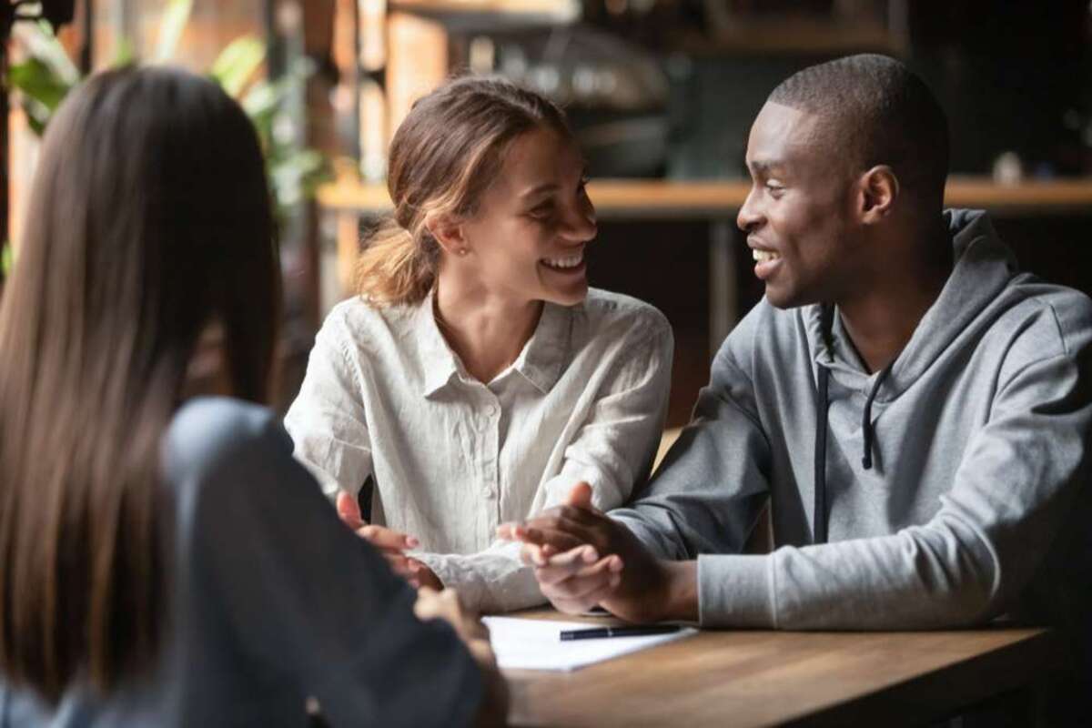 African man and mixed race woman couple feel happy great offer opportunity people looking at each other sitting in cafe with real estate agent female sign contract - featured_image