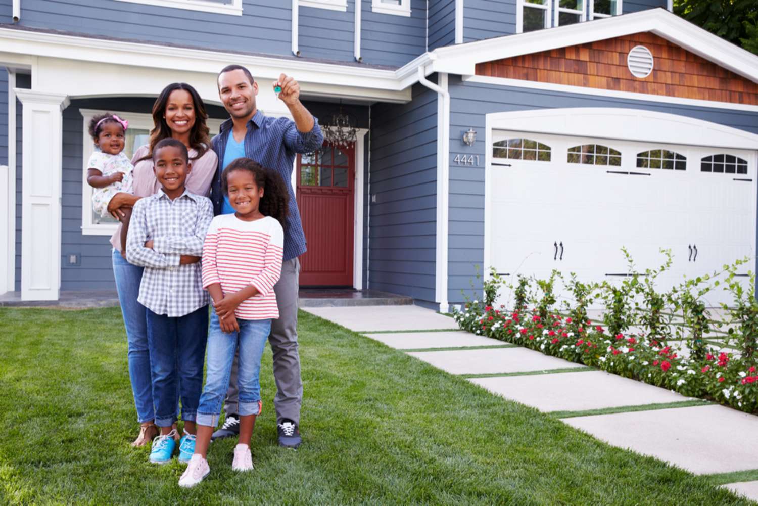 Happy black family standing outside their house, dad holding the key - featured_image